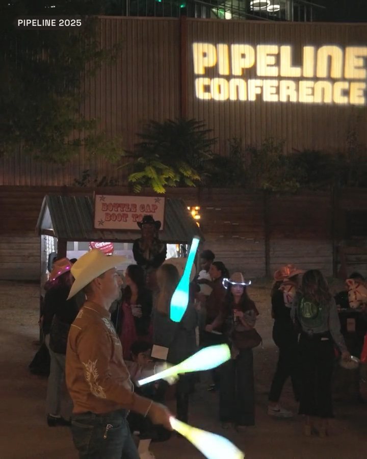 Attendees under a Pipeline Conference sign at night